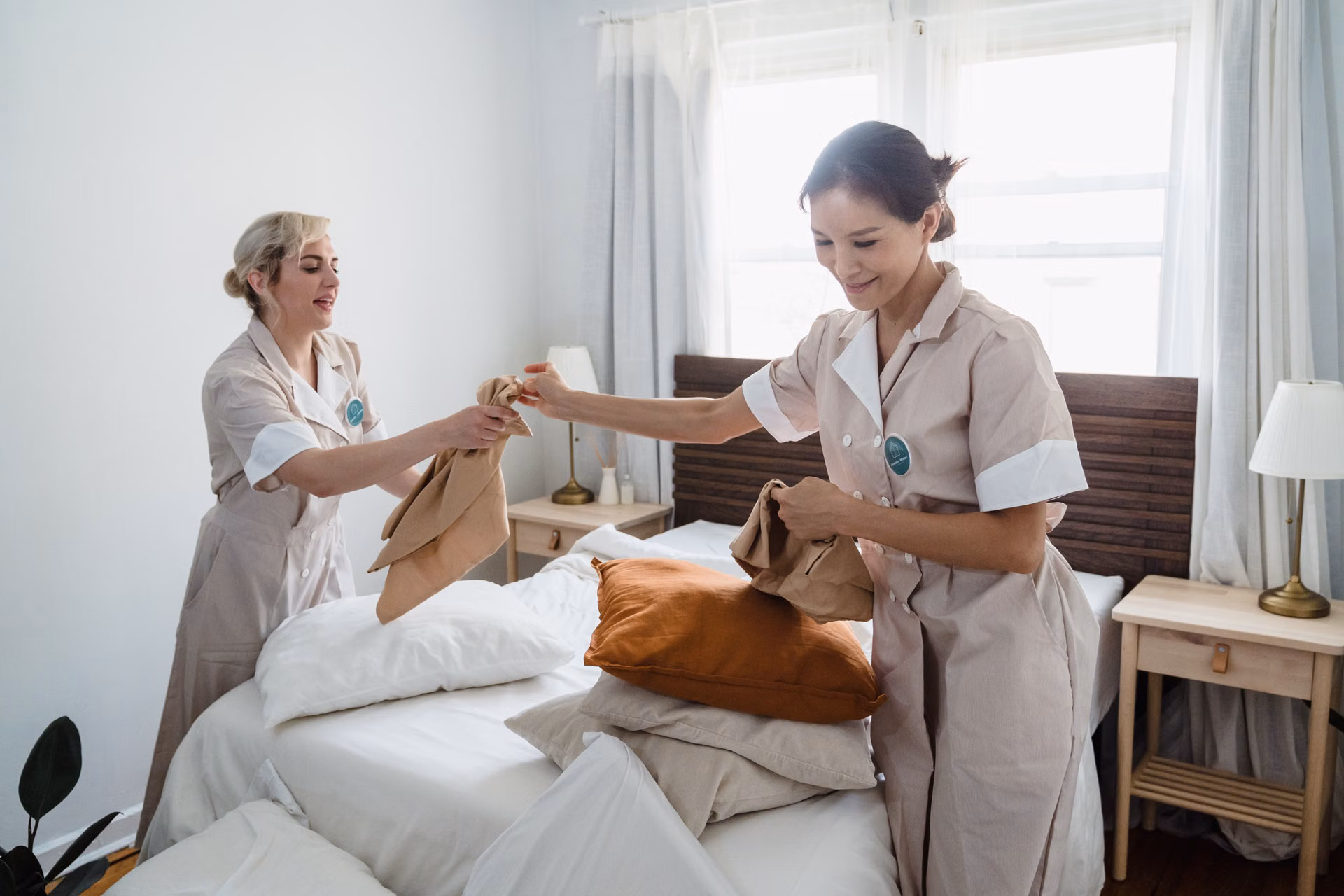 Two uniformed cleaners making a bed together