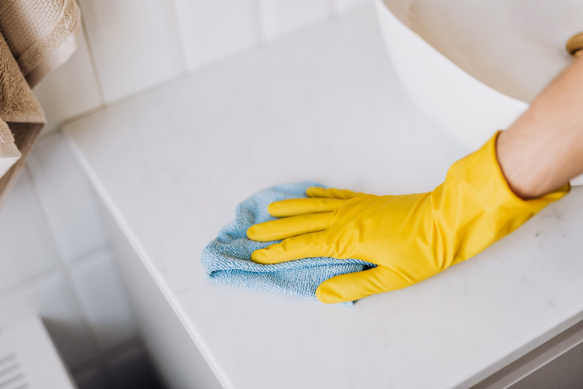 Gloved hand wiping a white bathroom counter to a shine