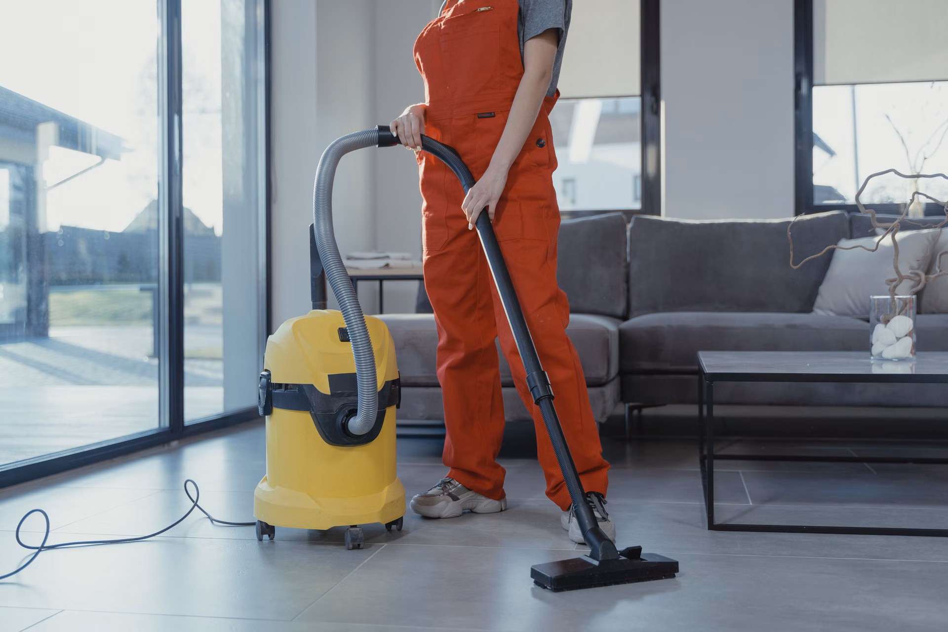 Cleaner vacuuming a bright modern living room