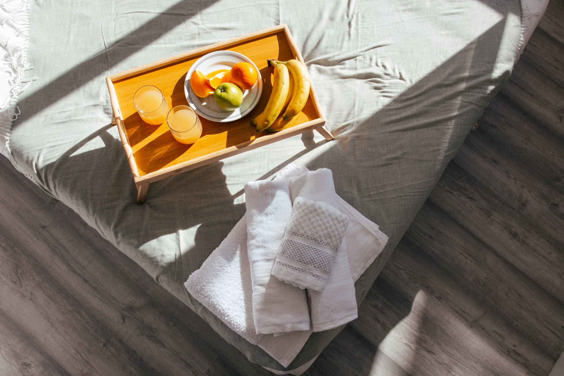 Fresh towels and a welcome tray laid out on a made bed