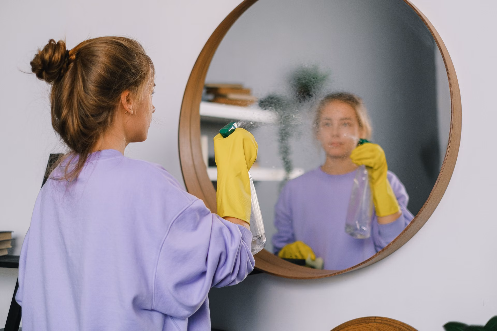 Cleaner wiping a round mirror until streak-free